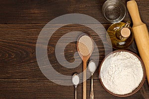 Ingredients for pizza dough on a dark rustic background.