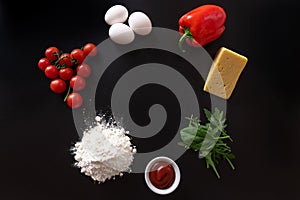 Ingredients for pizza laid out on a black background of isolate
