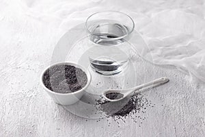 Ingredients for poppy milk. poppy seeds in bowl and glass of water on gray background