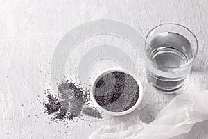 Ingredients for poppy milk. poppy seeds in bowl and glass of water on light gray background