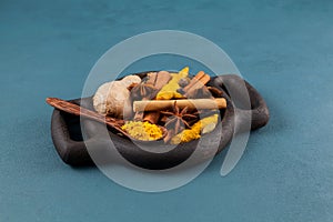 Ingredients for a popular Indian drink  Karak tea or Masala chai in wooden serving plate on blue background. Selective focus, copy