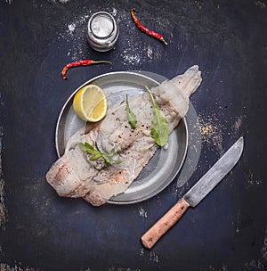 Ingredients for preparation of raw cod with herbs and lemon in a frying pan on wooden rustic background top view close up