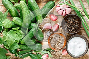 Ingredients for preservation on an old wooden table-cucumbers, garlic, dill seed, pepper, salt, seasonings and spices