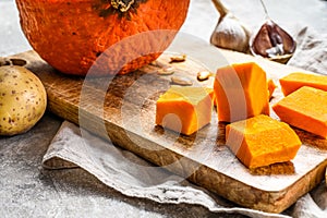 Ingredients for pumpkin soup. Gray  background. Chopped Pumpkin on rustic cutting board. Tasty and healthy food. Vegan food