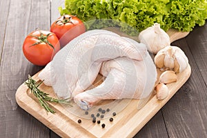 Ingredients and raw chicken leg on cutting board on wood table