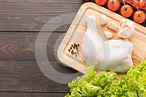 Ingredients and raw chicken leg on cutting board on wooden background