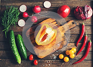 Ingredients for salad around cutting board. Fresh vegetables and herbs. Cooking