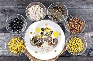 Ingredients for salad in transparent plates on a black wooden background. Fried champignons, olives, p