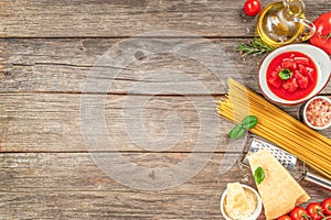 ingredients for Spaghetti pasta fresh cherry tomatoes, garlic, basil leaves, parmesan, olive oil on a wooden background