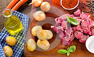 Ingredients for stew or goulash on old cutting board.