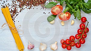 Ingredients for tasty pasta: raw cherry tomatoes, basil, garlic, pepper on the gray concrete kitchen table. Cooking concept