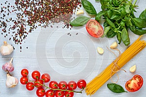 Ingredients for tasty pasta: raw cherry tomatoes, basil, garlic, pepper on the gray concrete kitchen table with space for text