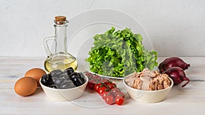 Ingredients for tasty tuna salad: canned tuna meat, fresh lettuce, boiled eggs, cherry tomatoes on the vine, black olives, red