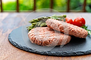 Ingredients for tasty vegan dinner, meat free plants based steak, green asparagus and red tomatoes