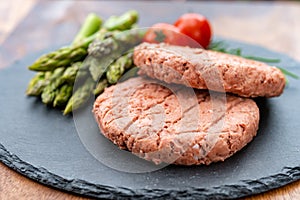 Ingredients for tasty vegan dinner, meat free plants based steak, green asparagus and red tomatoes