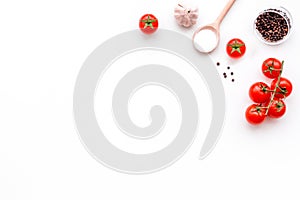 Ingredients for tomato sauce. Cherry tomatoes, garlic, black pepper, salt in spoon on white background top view copy