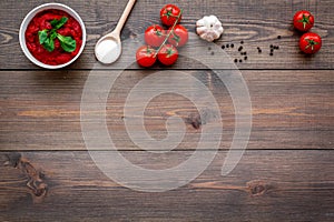 Ingredients for tomato sauce. Cherry tomatoes, garlic, green basil, black pepper, salt in spoon on dark wooden