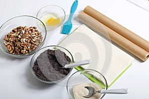 Ingredients and tools for making puff pastry curls stuffed with poppy and walnut. Are laid out on a white table top
