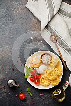 Ingredients for traditional Italian pasta dish. Uncooked raw tagliatelle bolognesi, parmesan cheese, olive oil, garlic, basil