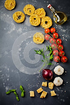 Ingredients for traditional Italian pasta dish. Uncooked raw tagliatelle bolognesi, parmesan cheese, olive oil, garlic, basil