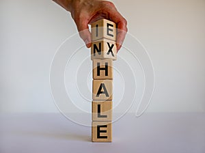 Inhale, Exhale concept. Hand turns cubes and changes the word `INHALE` to `EXHALE`. Beautiful white background. Copy space