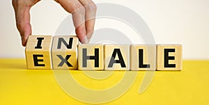 Inhale or exhale. Male hand flips wooden cubes and changes the inscription `exhale` to `inhale` or vice versa. Beautiful yello