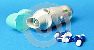 inhaler and pills against asthma on blue background. COPD photo
