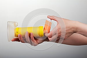 Inhaler spacer in the woman hands isolated on gray background