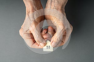 Inheritance concept. Elderly woman hands give a little toy house. photo