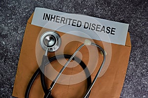 Inherited Disease text with document brown envelope and stethoscope isolated on office desk photo