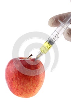 Injection into an apple. A hand in a medical glove with a syringe on a White background. Genetic modified foods. Injection of GMOs
