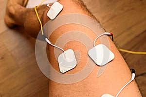 An injured athlete applies ems electrodes to his legs to recover muscle tone with a tensile electrostimulation system