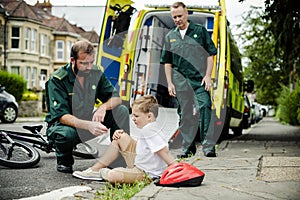 Injured boy getting help from paramedics photo