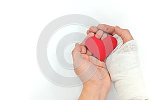 Injured hands holding a red heart in white background. Sacrificial and selfless love and genuine kindness concept.