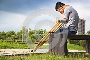 Injured Man with crutches sitting on a bench