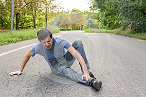 Injured man has broken leg and is sitting on road