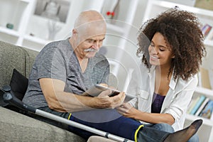 Injured man looking at digital tablet with young lady