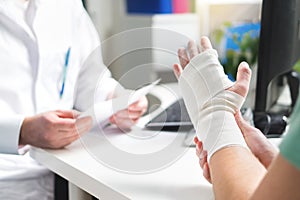 Injured patient showing doctor broken wrist and arm with bandage
