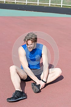 Injured runner on running track feeling pain of broken leg