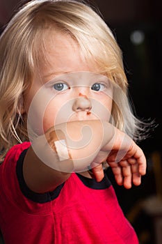 Injured sad boy with band aid on elbow