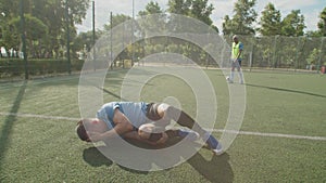 Injured soccer player in sportswear lying on football pitch after foul