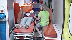 Injured woman lie on stretcher in ambulance car.