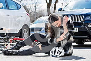 Injured woman sitting on the ground after bicycle accident