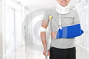 Injured young man use crutch and arm sling