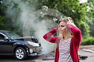 An injured young woman standing by the damaged car after a car accident.