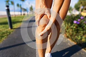 Injuries - sports running knee injury on woman. young woman with injured knee or leg outdoors.