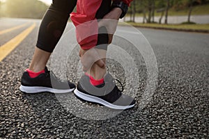 Injury female runner touching sprained ankle