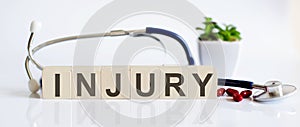 INJURY the word is written on the wooden cubes and sthetoscope and piils . Medical concept