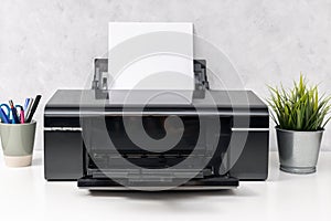 Inkjet printer with blank paper sheet on office desk