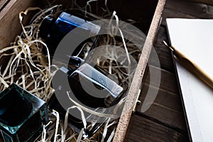 inks in a wooden box an empty notebook with a pen